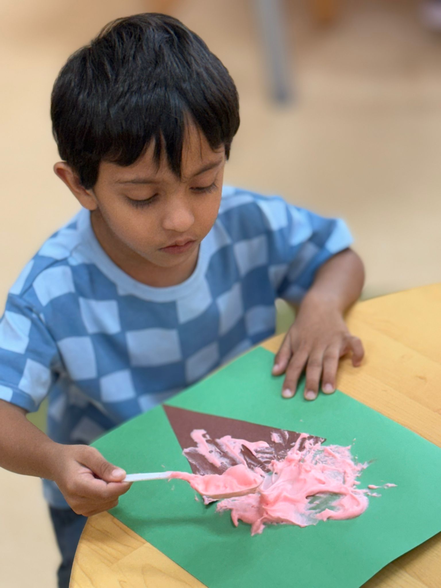 A student painting with pink paint on his craft