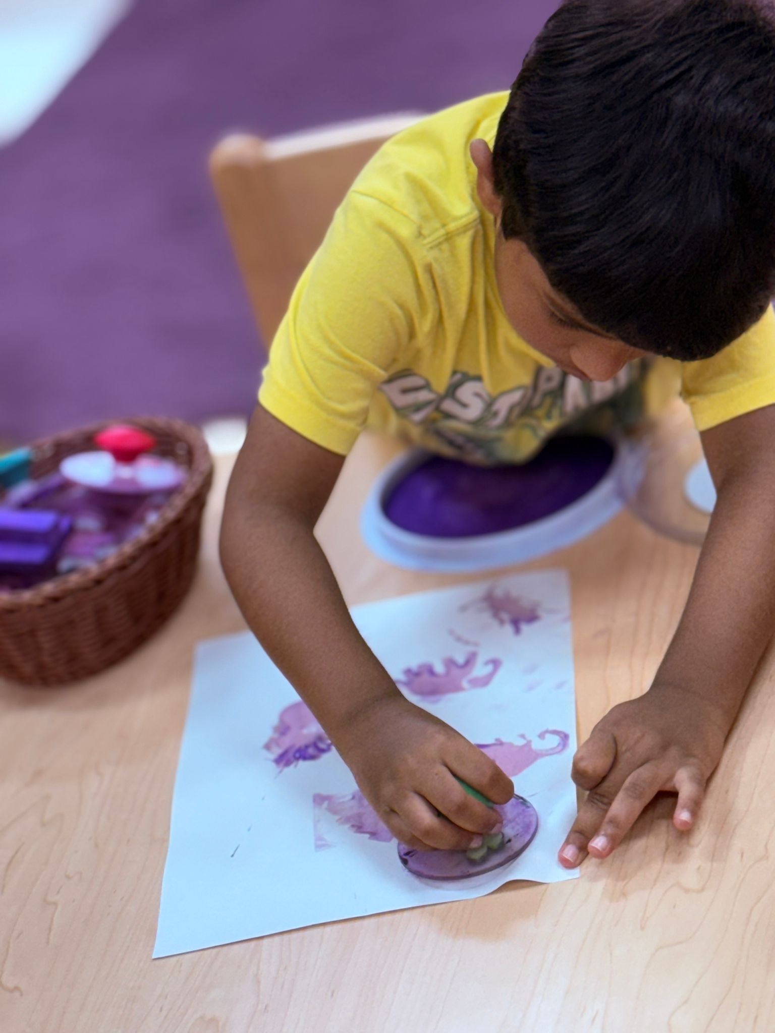 A student stamping purple paint artwork