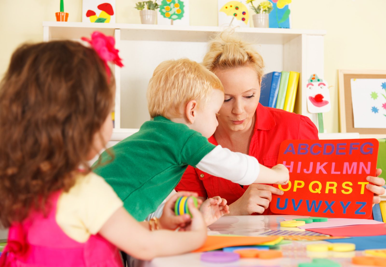 A teacher guiding young children through the alphabet