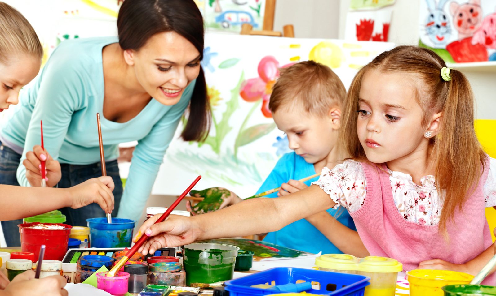 A teacher guiding students through a painting project